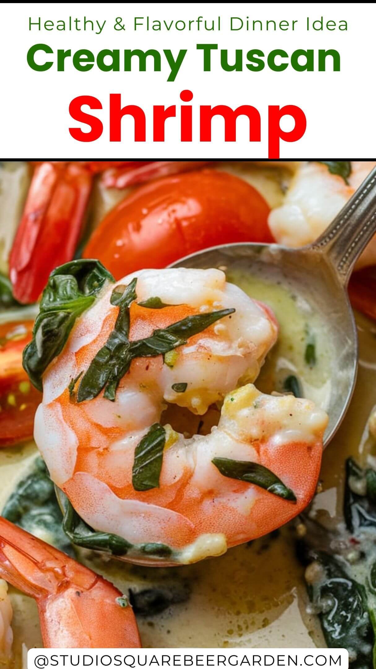 A close-up view of a dish containing shrimp, cherry tomatoes, and green leafy vegetables, possibly spinach or basil. The shrimp appear to be cooked in a creamy sauce, and the dish is garnished with herbs. A silver spoon is inserted into the dish, scooping up a piece of shrimp and some sauce. The overall presentation suggests a rich and flavorful meal.