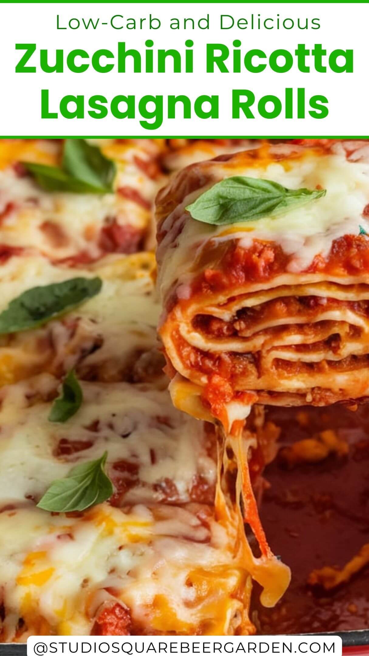 A photo of a red ceramic dish containing several roll-ups, possibly lasagna. One of the roll-ups is being lifted with a spatula, revealing its cheesy and gooey interior. The dish is placed on a white surface, and there's a white cloth with red stripes next to it. The roll-ups are generously topped with melted cheese and garnished with fresh herbs, possibly basil.