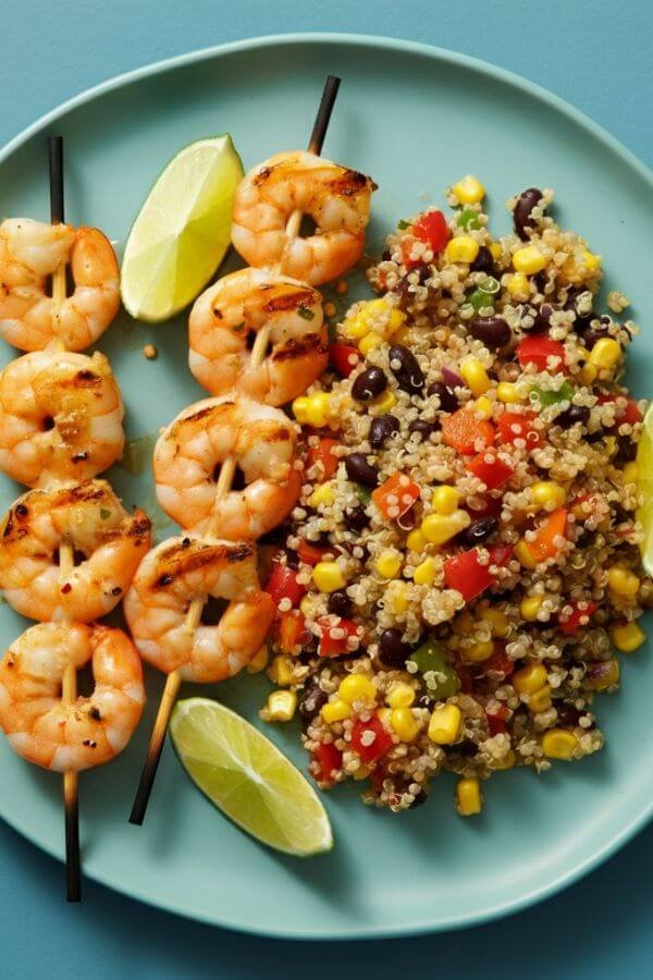 A vibrant plate of grilled shrimp skewers glistening with a honey-lime glaze, garnished with fresh lime wedges and sprinkled chili flakes, served alongside a colorful quinoa salad.