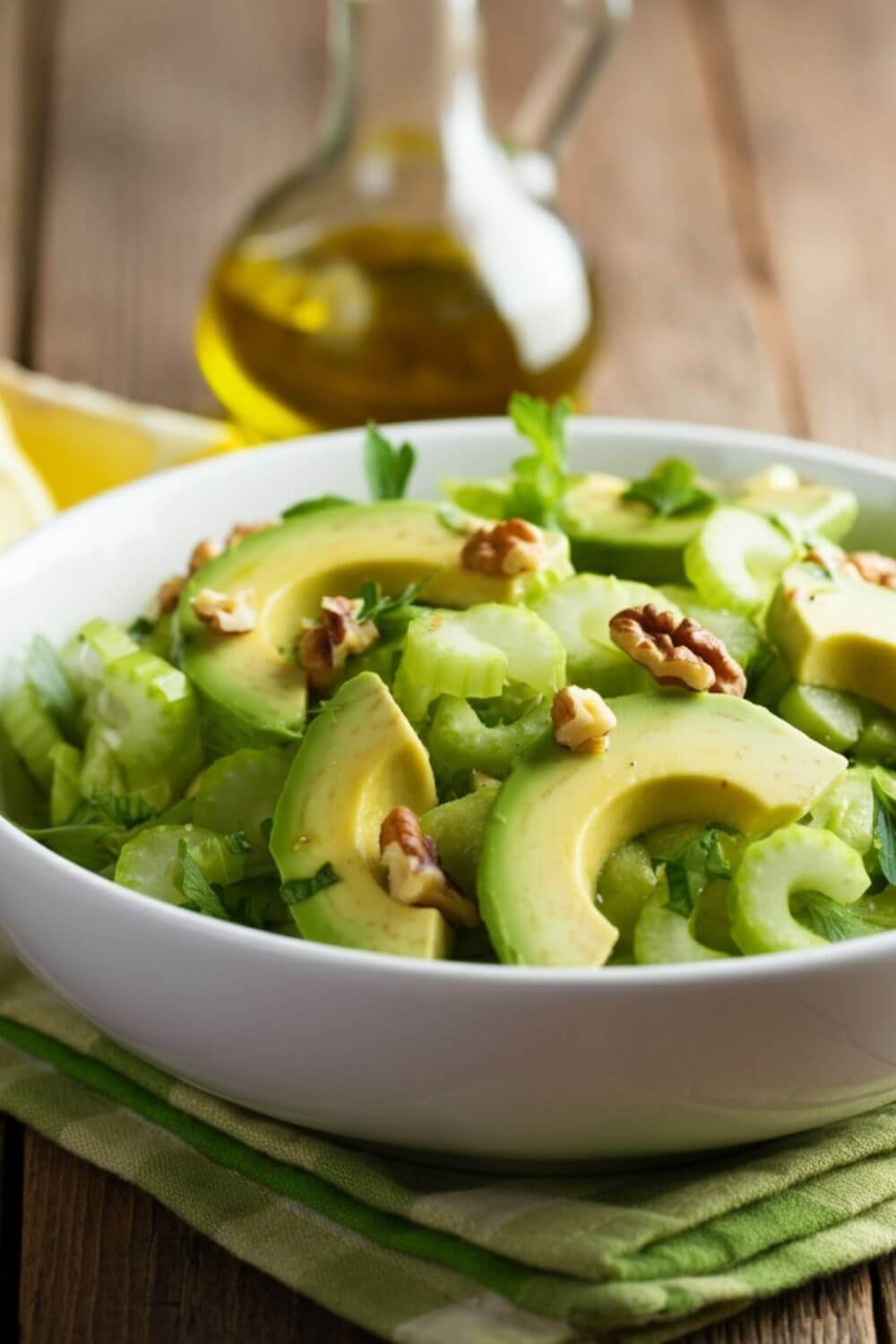 A fresh and vibrant Celery and Avocado Salad served in a white bowl. The salad features creamy avocado slices and thinly sliced celery, garnished with chopped fresh parsley and a drizzle of olive oil. Lemon wedges are placed nearby for a touch of brightness. Optional toasted walnuts are sprinkled on top for added crunch, with natural light highlighting the fresh, healthy ingredients.